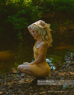 woman crouched at the edge of a wooded creek portrait photography