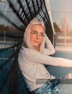 woman leaning against a tennis net at golden hour senior portrait photography
