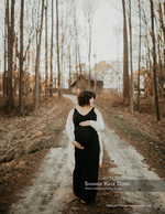 pregnant woman in black gown walking a wooded path maternity photography