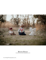 baby seated between two stuffed animals in the woods portrait photography