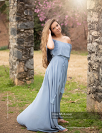 woman in a blue dress between stone pillars with cherry blossoms senior photography