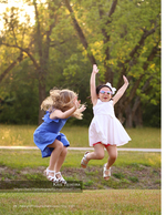 two girls jumping for joy in a park family photography