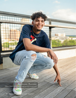 young man crouching on a rooftop deck senior portrait photography