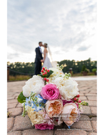wedding bouquet in the foreground with kissing couple bridal photography