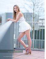 woman in white dress leaning on a rooftop railing senior portrait photography