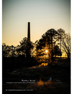 brick chimney silhouetted against a sunset through pines cityscape photography