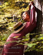 woman in a straw hat leaning against a tree in the forest portrait photography