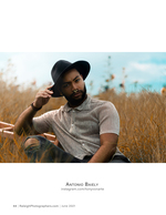 man in a black hat seated in a golden field portrait photography
