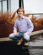 young man crouching on a rain-slicked rooftop deck senior portrait photography