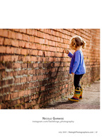 toddler dragging her fingers along a brick wall family photography