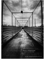 fenced pedestrian bridge walkway in black and white cityscape photography