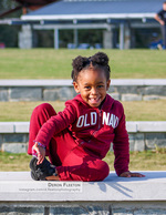 girl seated on a stone wall in a park family photography
