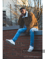 young man seated on a brick rooftop ledge senior portrait photography