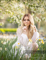 woman smelling a daffodil in a blooming garden portrait photography