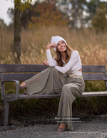 woman in a knit beanie seated on a park bench portrait photography