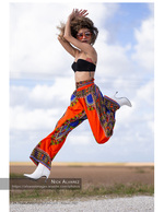 woman jumping in patterned harem pants against an open sky fashion photography