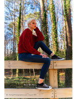 woman in a red sweater seated on a wooden fence rail portrait photography