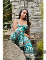 woman in a printed dress seated against a stone wall portrait photography