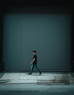 man walking past a roll-down shutter street photography
