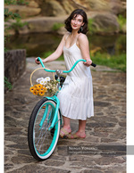 woman with a flower-basket cruiser bike on a stone path portrait photography