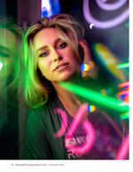 woman lit by green and pink neon signs portrait photography