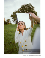woman holding up a mirror in a grassy field portrait photography
