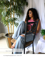 woman seated in a chair beside potted palms portrait photography