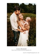 father kissing mother's head as she holds their baby in a field family photography