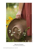 hand holding a wide-brim hat among black-eyed susans fashion detail photography