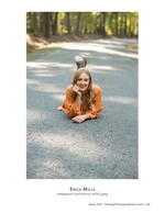 woman in an orange dress lying on a forest road senior portrait photography