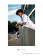 graduate leaning on a railing holding track cleats portrait photography
