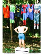 little boy gazing up at superhero costumes on a clothesline children's portrait photography