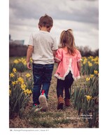 brother and sister walking hand in hand through daffodils children's portrait photography
