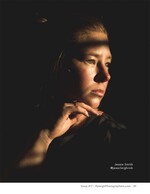 woman's face lit by a single beam of light portrait photography