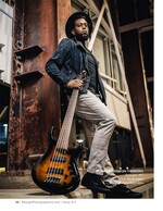 man in a fedora leaning against steel beams with a bass guitar portrait photography