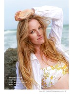 model with wind-blown hair shading her eyes on a rocky beach fashion photography